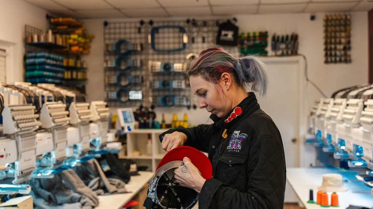 4Winners Merch team member embroidering a red cap at the Las Vegas production shop