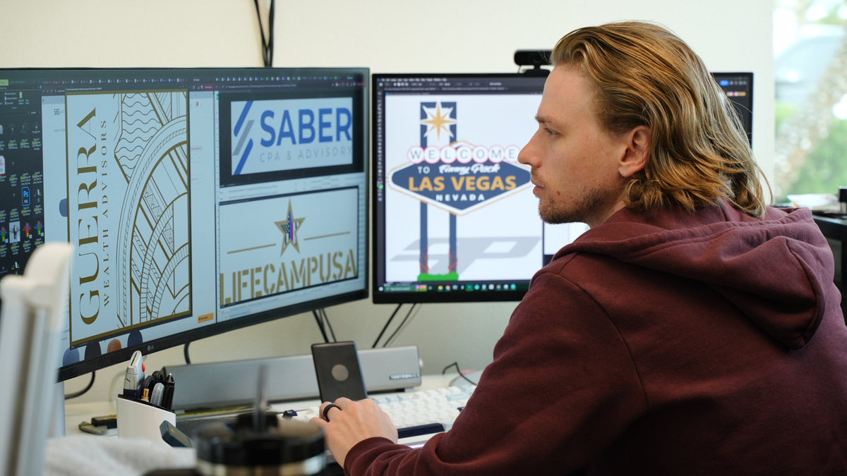 4Winners Merch graphic designer creating custom client artwork at a dual-monitor workstation