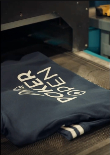 Navy ARIA Poker Open hoodie being screen printed on a heat press machine at 4Winners Merch
