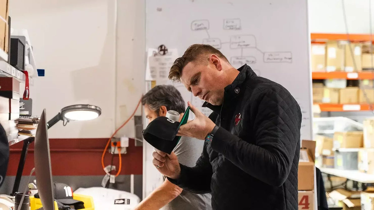 4Winners Merch team member inspecting an embroidered cap in the production facility